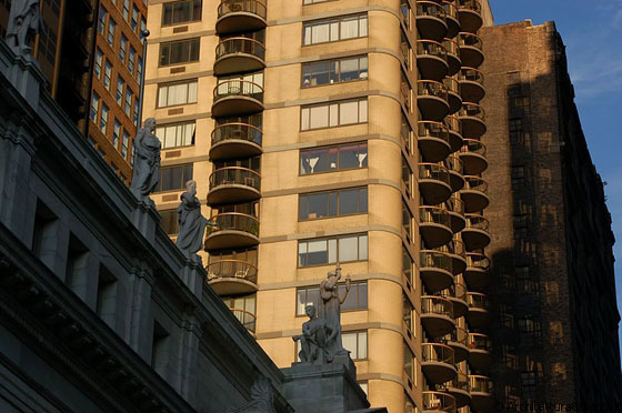 MIDTOWN MANHATTAN - Il profilo di eleganti statue si staglia sul vicino grattacielo scaldato dalla luce del tramonto
