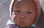 LEH . Città vecchia: un piccolo bambino tibetano fuori dalla porta di casa si appoggia ad una tanica timidamente incuriosito dalla nostra presenza