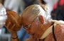 SRI VEERAMAKALIAMMAN TEMPLE. Questa anziana induista prega battendo sulla sua fronte una noce di cocco, simbolo della distruzione dell'ego