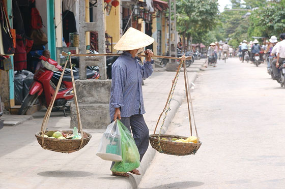 HOI AN - Vietnamiti trasportano frutta e verdura nei tipici cesti a bilanciere