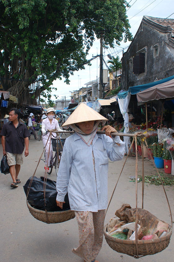 VIETNAM CENTRALE - Una donna trasporta merce al mercato centrale di Hoi An con i tipici cesti a bilanciere in spalla