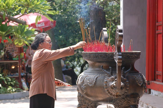 HANOI - Una fedele buddhista brucia incenso in un bel bruciatore di bronzo nel cortile del Tempio di Ngoc Son
