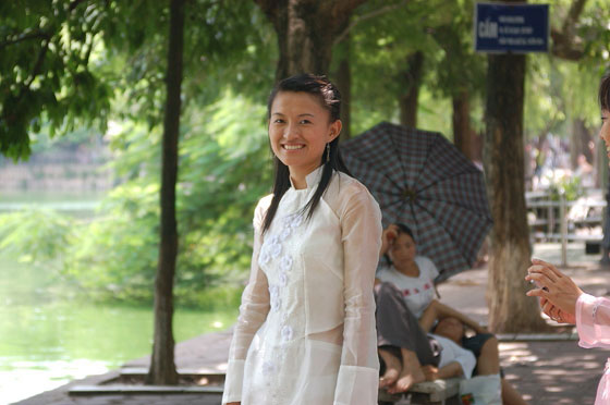 HANOI - Una giovane vietnamita vestita con abiti tradizionali di color bianco sulle rive del lago Hoan Kiem 