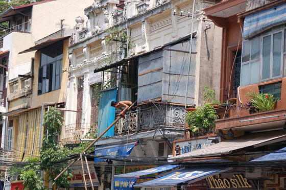HANOI - Uomini intenti a sollevare un grande palo dal balconcino