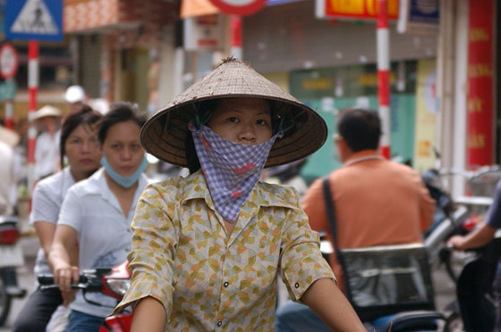 HANOI - Passeggiando per le strade del Quartiere Vecchio si incontrano donne in bicicletta con foulard alla bocca e non bai tho