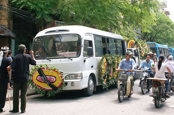 HANOI - La processione di un funerale: tre bus trasportano familiari e conoscenti del defunto e seguono gli uomini a piedi