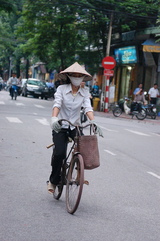 HANOI - Donna in biciletta con foulard alla bocca e 