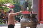 HANOI. Una fedele buddhista brucia incenso in un bel bruciatore di bronzo nel cortile del Tempio di Ngoc Son