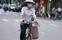 HANOI. Donna in biciletta con foulard alla bocca e non bai tho in testa
